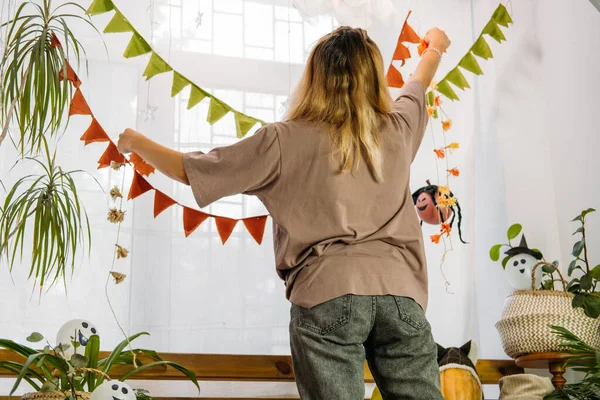 Młoda kobieta urządza dom na Halloween. Wnętrze domu urządzone na Halloween z balonem i rośliną domową DIY w naturalnym, zerowym stylu odpadów — Zdjęcie stockowe