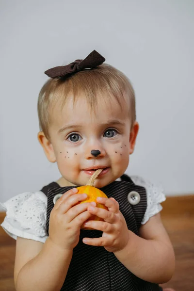 Ideas de maquillaje de Acción de Gracias de Halloween para niños y bebés. Feliz bebé divertido con una calabaza en el fondo de la casa —  Fotos de Stock