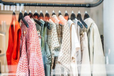 Siyah askılarda çeşitli kadın kıyafetleri var. Çekler, çiçekler ve vitrindeki tarafsızlar da var. Yavaş moda, dikkatli gardıroplar, sürdürülebilir alışveriş alışkanlıkları, küratörlü dolap. Yüksek kalite fotoğraf