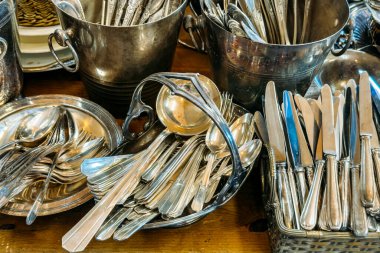 Sepet ve tepside sıralanmış bıçak, çatal ve kaşıklardan oluşan gümüş çatal bıçak koleksiyonu. İkinci el çatal bıçak takımı, kaliteli sofra takımı, zarif bir yemek dirilişi, aile yadigarı sofra takımı. Yüksek kalite fotoğraf