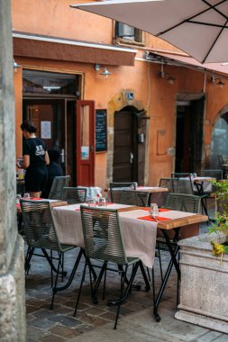 19 Ağustos 2025 'te Vieux Lyon, Fransa' da kırsal turuncu cepheli ve gözlüklü ve kırmızı peçeteli bir restoranın büyüleyici açık hava yemek terası. Yüksek kalite fotoğraf