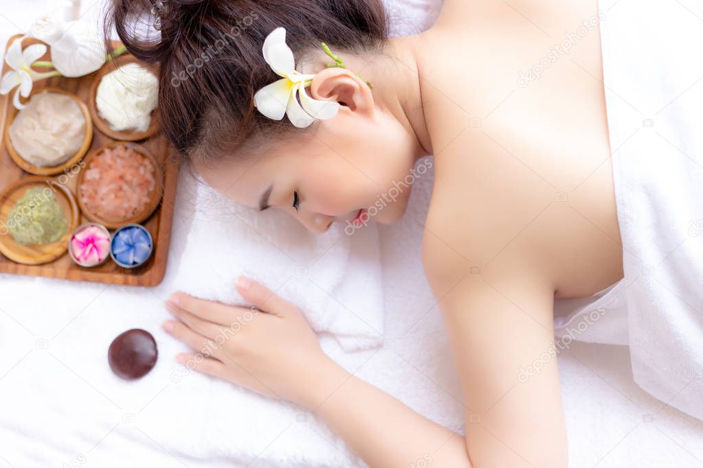 Charming beautiful woman lying down on bed, feels relaxed, comfortable, happy at aromatherapy, spa shop with herbal background. Photo can use for advertising of spa, hotel, resort, beauty or salon.