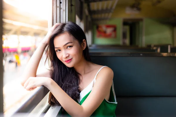 Attractive beautiful woman is looking someone. Charming asian woman feel relaxed, comfortable and happy because she is traveling by retro train. It is low cost transportation. She get smile. copy space