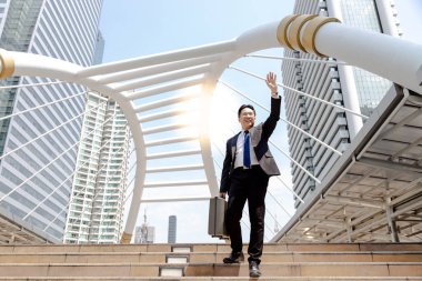 Yakışıklı bir iş adamı tebrik veya söyleyerek Merhaba onun arkadaş ya da müşteri. Sevimli adam birini karşılamak ne zaman mutlu hissediyor. Metropolis ofisinin kopya alanı ve şehir arka plan ile adımlar üzerinde yürüyecek