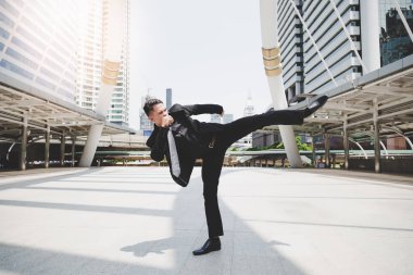 Yakışıklı işadamı olsun onun patron ve stres rahatlatmak istiyor kızgın ve öfkeli. Cool adam havada tekme tarafından egzersiz olduğunu. Çekici erkek takım elbise, kravat, uzun pantolon giyer. Cityscape arka plan