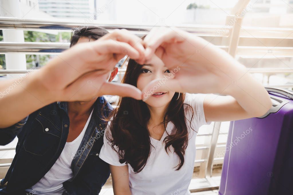 Portrait traveler couple. Handsome boyfriend and beautiful girlfriend is making symbol of love by using their hand and finger for making a shape of heart. They have honeymoon and special time together