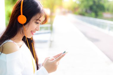 Güzel genç kadın büyüleyici hayat dinle güzel müzik tarafından keyif alıyor. Güzel kız bakmak smartphone ve onun favori müzik bulma. O kulaklık giymek. Güzel genç kız güzel gülümsemesi var. kopya alanı