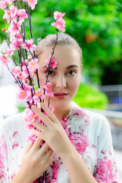 Portrait charming beautiful woman. Attractive girl has beautiful face and nice skin. Gorgeous woman looks so charming. Pretty girl holds pink flowers at a park. She looks so beautiful like a flower.