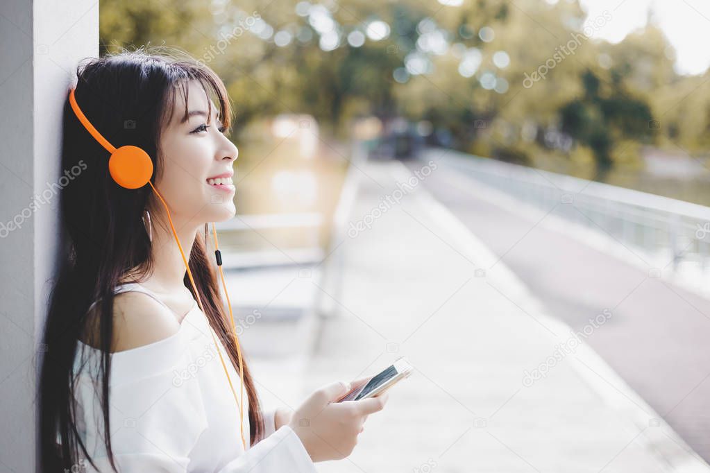 Portrait pretty young woman listening music. Charming beautiful woman enjoy listening music on phone at park in winter time that make her feeling relaxed, happy, fresh with smiley face. copy space