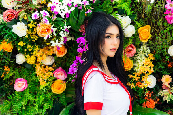 Portrait charming beautiful sexy woman. Attractive beautiful sexy girl is standing in front of beautiful flowers or blossoms. Gorgeous woman has nice skin and nice face. Pretty woman feels relaxing