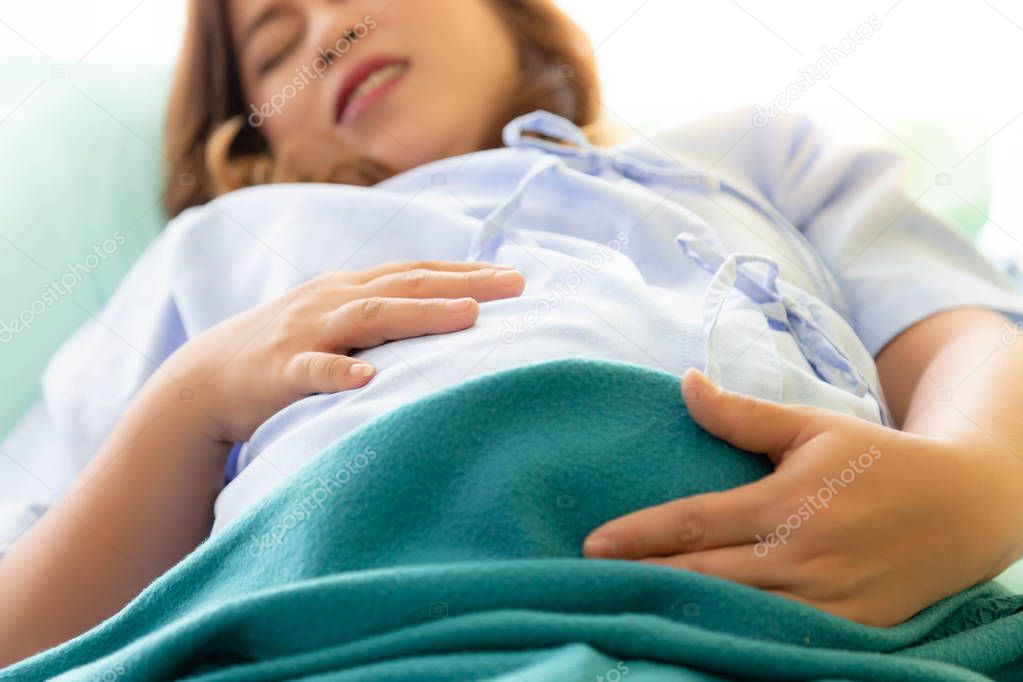 Pregnant woman gets painful or hurt of her belly. Mother gets suffered because mother nearly gives birth her baby or children. It is the first time of her life. It's sign of preterm infant. suffer face
