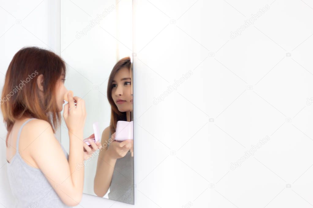 Beautiful Asia woman apply or put on makeup to her beautiful face for concealing wrinkles, blemish, pores by using makeup sponge, pressed powder for smooth skin face. Women look at mirror. copy space