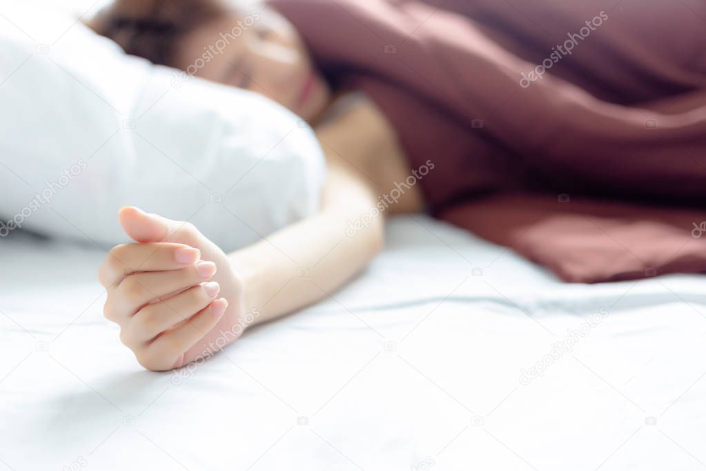 Attractive beautiful woman is sleeping on a bed at bedroom. It is nearly afternoon but she is still sleeping on the bed because pretty woman does not have to go to work, it is weekend holiday. copy space
