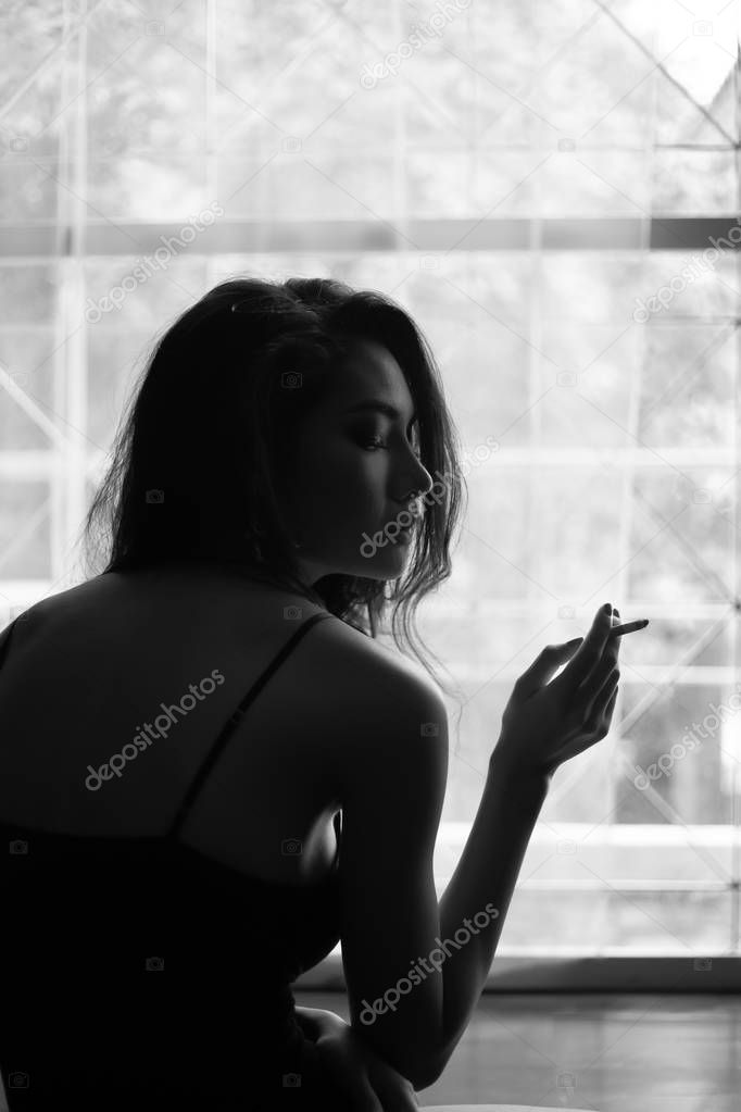 Portrait charming beautiful sexy woman. Attractive beautiful girl smoke cigarette in dark room at home. Glamour women feels happy, relaxing and comfortable. Gorgeous asian woman has nice face and body