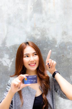 Attractive beautiful woman is pointing finger to copy space above her head and charming beautiful girl show credit card. Gorgeous woman has freedom for paying product, goods, service and satisfy it clipart
