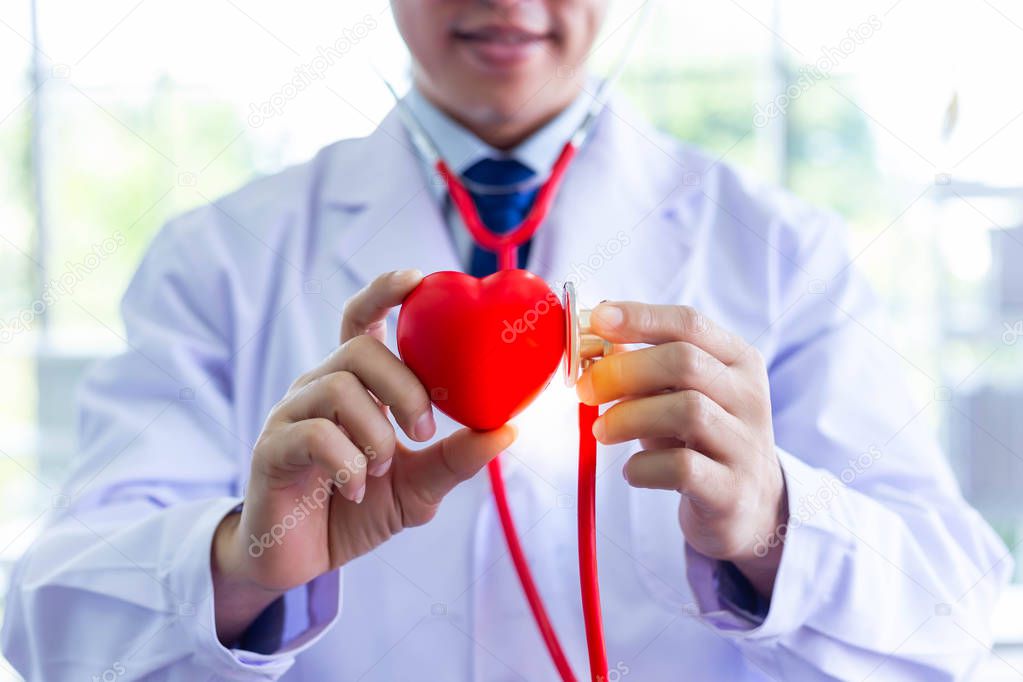 Doctor is holding heart and using stethoscope for examining fake heart at hospital room. Doctor who wants telling everyone take care their health by exercise for protecting heart attack, arrhythmia.