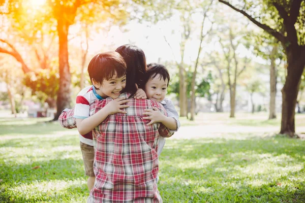 Beautiful mother or single mom is hugging her children or boys and older brother and younger brother are hugging their mom with love. It looks so warm family. Lovely children do not have father