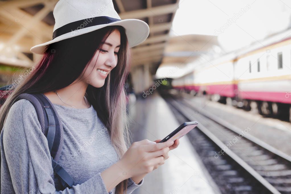 Charming beautiful traveler woman is searching interesting place or the way for traveling on smartphone by using some application on internet online service. Attractive beautiful girl get happy, smile