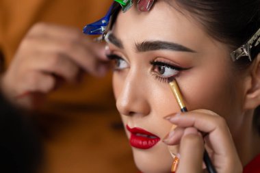 Güzel model çekici önce mükemmel makyaj yapmak için eyeliner fırçası kullanarak su hattı için makyaj sanatçı uygulanan göz kalemi yapmak onun iş. Çekici güzel kız mükemmel yüzü, güzel gözleri var
