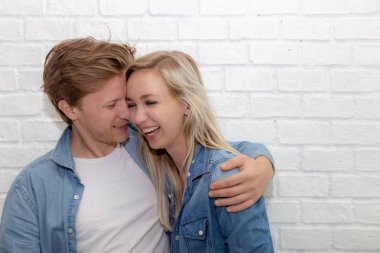 Çekici çift mutlu hissediyorum ve rahatla. Çekici yakışıklı genç adam kucaklama kız arkadaşı ve birlikte gülüyor. Erkek ve kız kot gömlek giymek. Cool adam, kadın love her diğer. kopya alanı