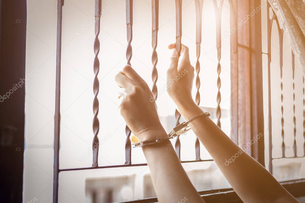 Asian woman or detainees girl looking through the window and asking for help. Poor woman get nervous, scared, hopeless. Asia girl is cuffed by traffickers or kidnapper. She live with suffering