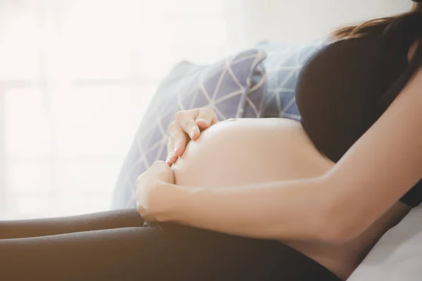 Portré szép terhes nő. Vonzó szép anya megérintette a hasát, és leül az ágyon a várakozó orvos ellenőrzésére, vagy vizsgálja meg magzat vagy baba. A terhes lány jövő hónapban szülni fog — Stock Fotó