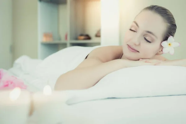 Attractive beautiful woman lay down on bed at spa salon. Charming beautiful young girl get relaxing, happiness. Customer woman is sleeping in spa room at spa salon with nice scented candles smell