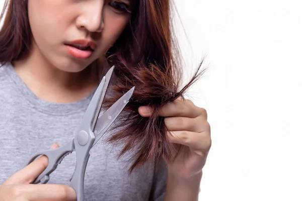 Hermosa mujer asiática joven recortando o cortando sus puntas abiertas de las puntas del pelo. Atractiva hermosa señorita obtener problemas de su cabello. Hermosa chica conseguir el pelo dañado. Ella se enoja, infeliz. aislado — Foto de Stock