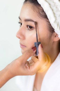 Sanatçı güzel kaşına güzel bir fırça kullanarak göz farı sürüyor. Güzel bir kadın düğün törenine katılmadan önce. Makyaj yapan genç Asyalı güzel bir yüz portresi. Gelinin cildi güzel, yüzü güzel.
