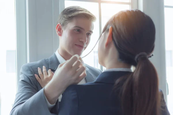 Businessman flirting secretary woman, look each other, passionate. Manager seducing an attractive sexy office girl. Man touch mistress hair, looking his girlfriend during conversation in cozy office