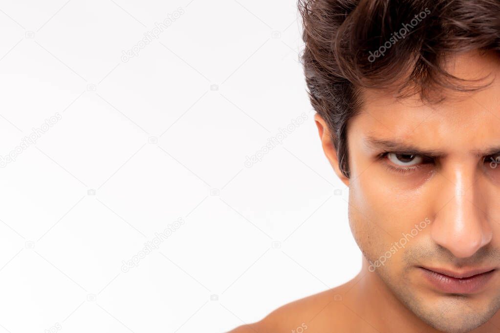 Confident, determined handsome young guy. Handsome young Caucasian man looks at camera. Male get angry, mad face. Closeup half face. He has strong mind. isolated on white background, copy space