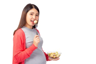 Meyve salatası yiyen hamile genç Asyalı kadın bebek ve fetüs için sağlıklı bir yemektir. Hamile annenin elinde meyve salatası var. Hamilelik, doğum öncesi, annelik, sağlık konsepti