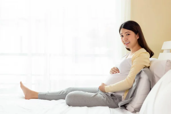 快乐怀孕的年轻亚洲女人摸着肚子 开心地笑着爱她的孩子或胎儿 看着相机 待产和待产的怀孕少女有很好的健康怀孕 母性观念 — 图库照片