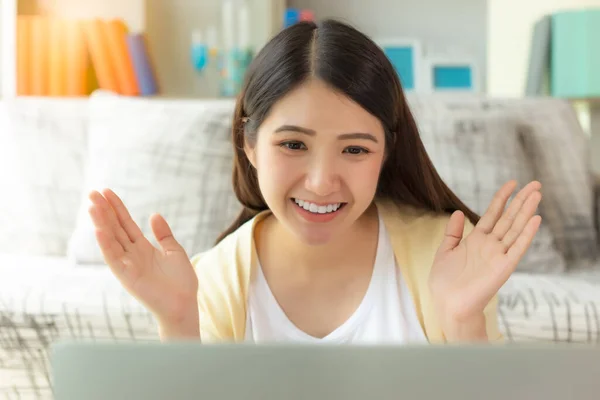 Young Asian girl chatting and talking with family friend on virtual video conference meeting with video call during stay at home or quarantine and social distancing in living room at home with smile