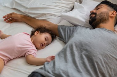 Yatakta babasının yanında uyuyan küçük bir kız. Bekar baba yorulur ve sevgili küçük kızıyla yatar. Sevimli küçük kız iyi uyudu ve rahatladı.