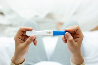 Hamilelik testi yapan mutlu hamile kadın, pozitif testi incele, genç bayanın karnında bebek ya da fetüs var. Genç anne yeni doğmuş bebeği bekliyor, hamilelik, annelik, konsept bekliyor.