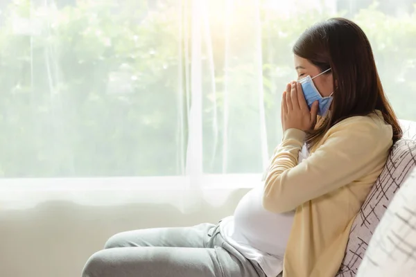 Pregnant Asia mother get sick of cold or flu and coughing Young pregnant asian woman in face mask stay alone at home for self quarantine. home quarantine, prevention covid 19, coronavirus concept