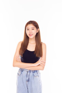 Çekici bir Asyalı genç kadın portresi. Güzel kız kollarını kavuşturdu ve kendine güvenen gülen yüz ifadesi takındı. Güzel bayan yaz mevsiminde kot pantolon ve yelek giyer. Beyaz arka planda izole edilmiş. moda kızı