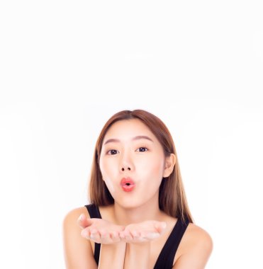 Güzel, genç Asyalı bir kadın beyaz arka planda izole bir şekilde hava öpücüğü yolluyor ve üflüyor. İyi hissettiğinin bir göstergesi. Uzakta vedalaşıyor. Genç ve güzel bir kadın hava öpücüğü veriyor. Yukarıdaki alanı kopyala