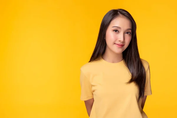 Portret młodej Azjatki, Piękna dziewczyna nosi żółtą koszulkę z żółtym tłem, przestrzeń na ksero w studio. Ładna azjatycka kobieta staje się pewna siebie. Ma długie włosy. — Zdjęcie stockowe