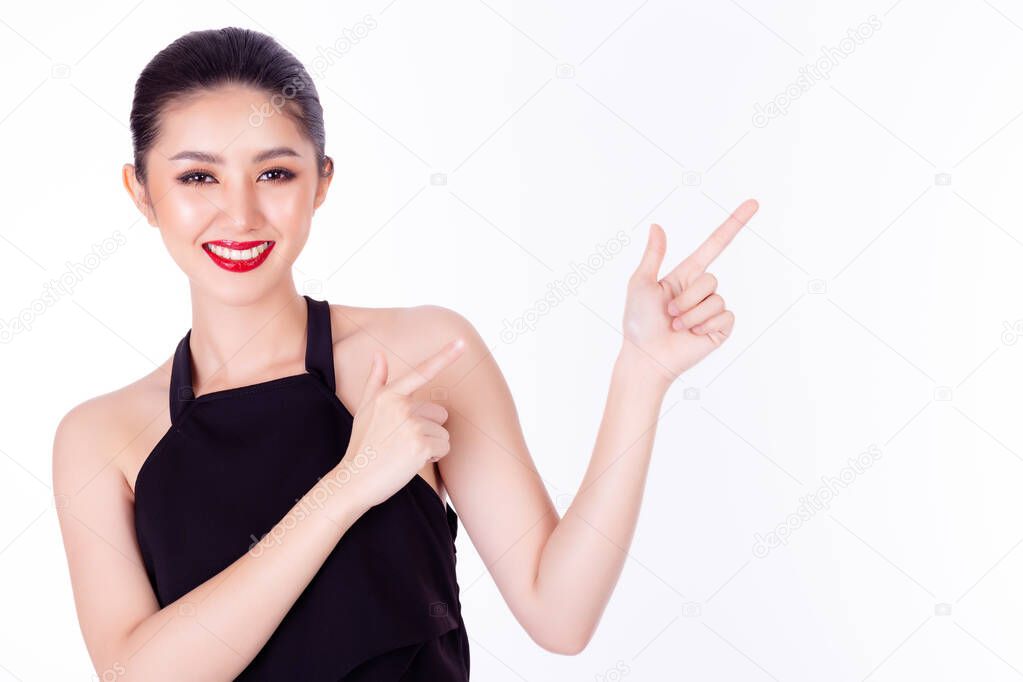 Beautiful young Asian woman pointing up to copy space and looking at camera with smile face Glamour woman apply red lipstick on her beautiful lips and act like a satisfied product use for advertising 