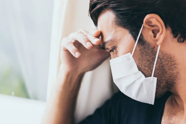 Upset depressed melancholy sad crying man in protective face mask with crying during serious illness, coronavirus outbreak and flu covid19 epidemic. Patient guy stay at hospital, get stress, lonely