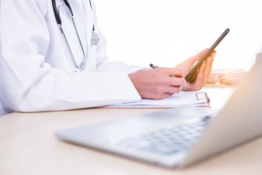Tanımlanamayan doktor hastanedeki doktor ofisinde akıllı telefon kullanıyor, hastaya mesaj yazıyor, tedavi öneriyor. Doktor, hastanın tıbbi testinin ve reçeteli yazının sonuçlarını okuyor.