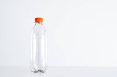 Tek boş plastik su izole parlak beyaz zemin, turuncu kapak, kapak karşı şişe