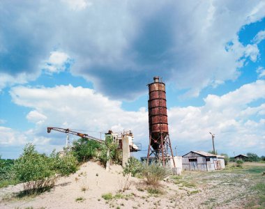 Silo ve endüstriyel makine, bina, kum, bulutlar, mavi gökyüzü terk edilmiş