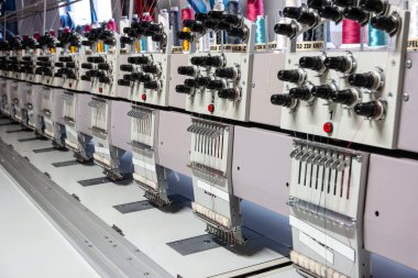 Çok başlı endüstriyel dikiş makinesi küçük bir fabrika deposunun içini kapatıyor..