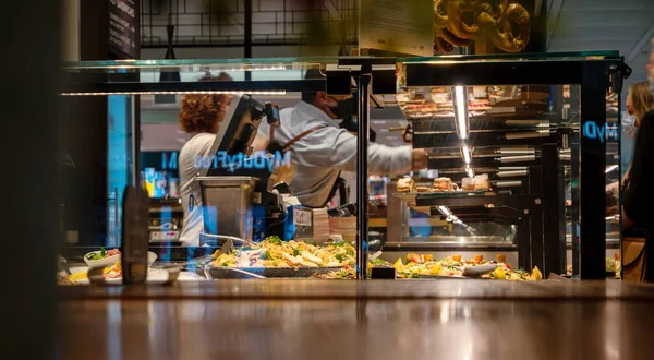 Fast food behind the window of an airport diner servers wearing face masks during global pandemic no recognizable faces 2020