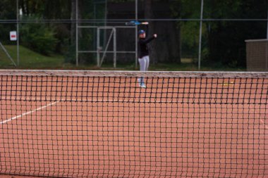 Tenis kortunun ağ örgüsü, arka planda bulanık kadın oyuncuyla birlikte öne yakın..