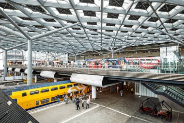 Lahey, Hollanda, 26 Ağustos 2025. Tren istasyonunun modern binasının içinde askıya alınmış tren platformu var. Geniş açı, insanlar bekliyor.