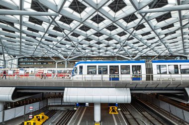 Lahey, Hollanda, 26 Ağustos 2025. Tren istasyonunun modern binasının içinde askıya alınmış tren platformu var. Geniş açı, insanlar bekliyor.